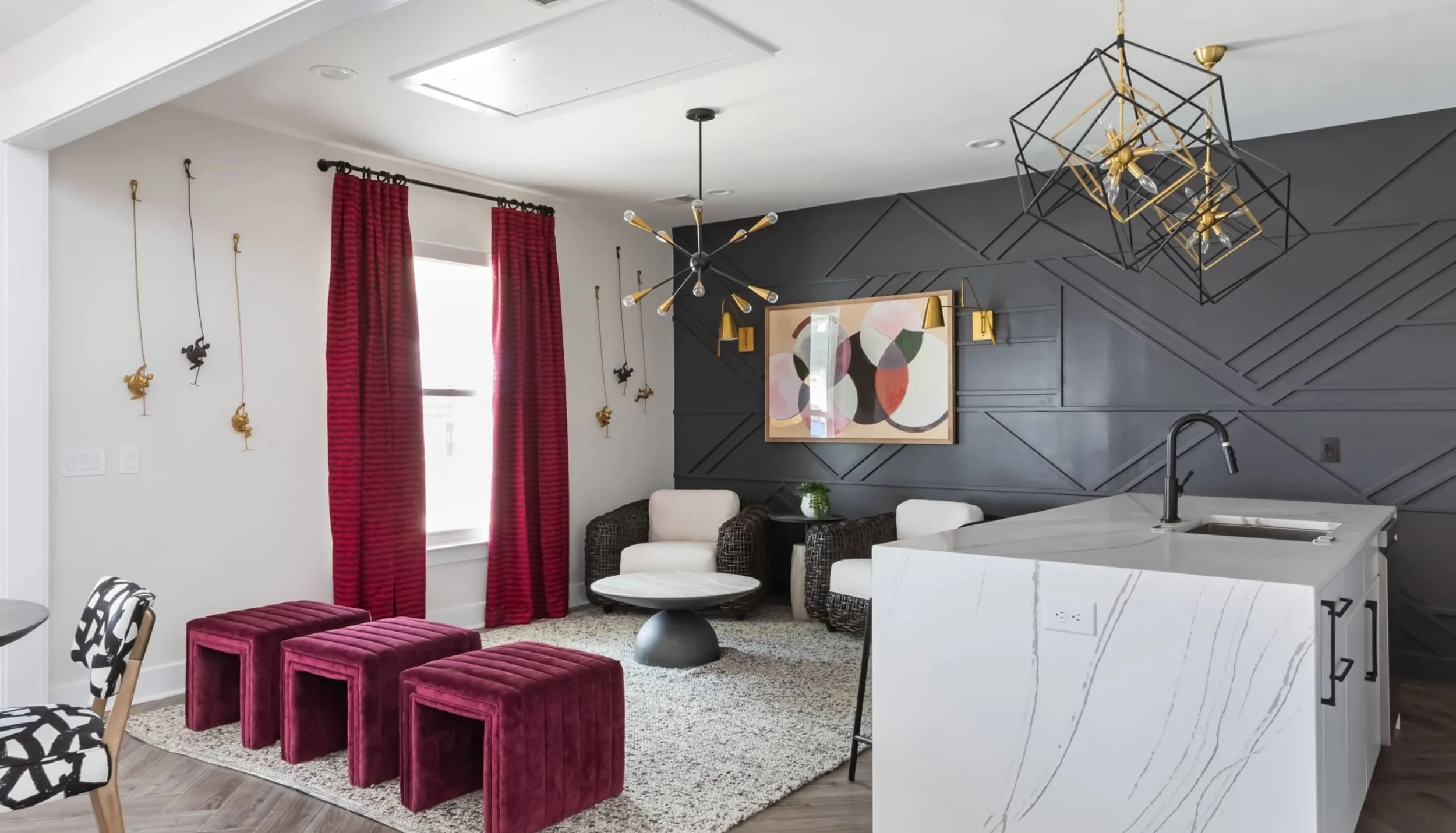 Lounge and bar with a charcoal geometric panelled wall, raspberry velvet stools, brass cube chandeliers and a quartz waterfall bar